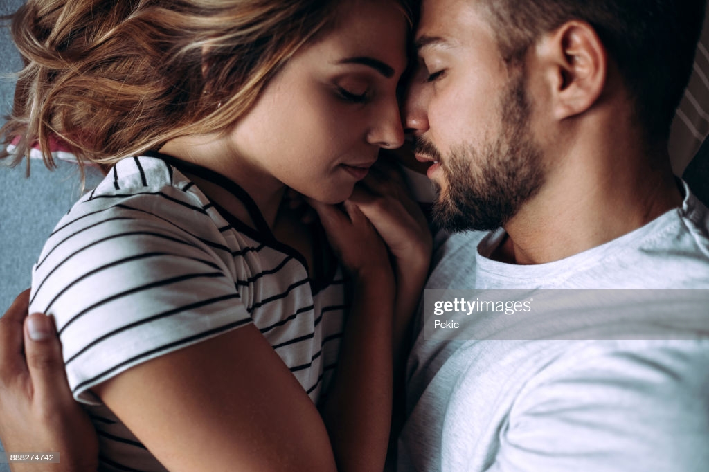 Attractive Young Couple Laying In Bed In Consoling Embrace